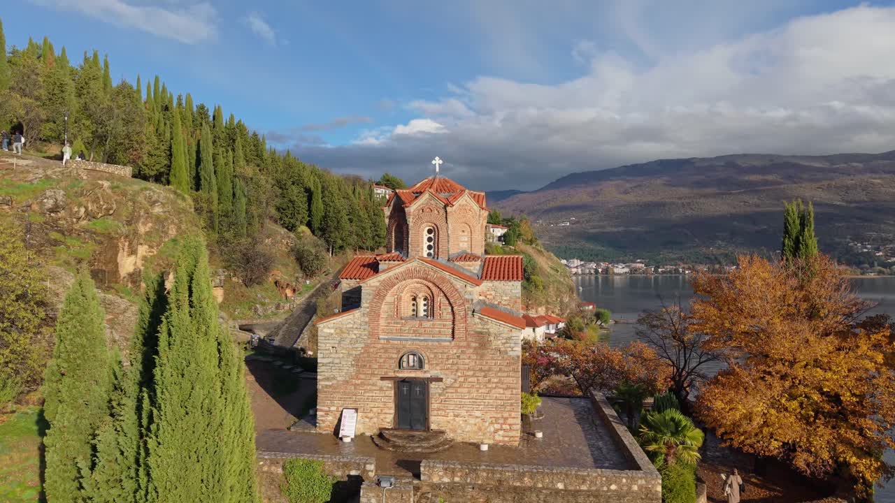 Una panoramica della storica chiesa di San Giovanni a Kaneo. Il drone si muove sulle scogliere rocciose del Lago di Ocrida in una giornata luminosa e soleggiata, mettendo in mostra la splendida architettura bizantina
