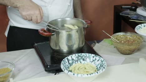 el chef cocinando en agua hirviendo pasta italiana hecha a mano