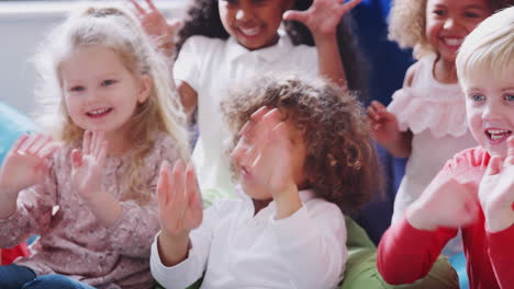 Infant-school-children-in-a-comfortable-corner-of-the-classroom-waving-to-their-teacher,-close-up
