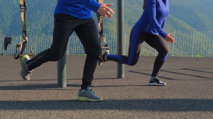 Couple doing suspension leg exercises outdoors