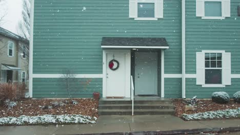 a cinematic scene captures the snow in slow motion within a residential setting, a street adorned with a staircase leading to a building entrance, set against a somber and overcast weather backdrop