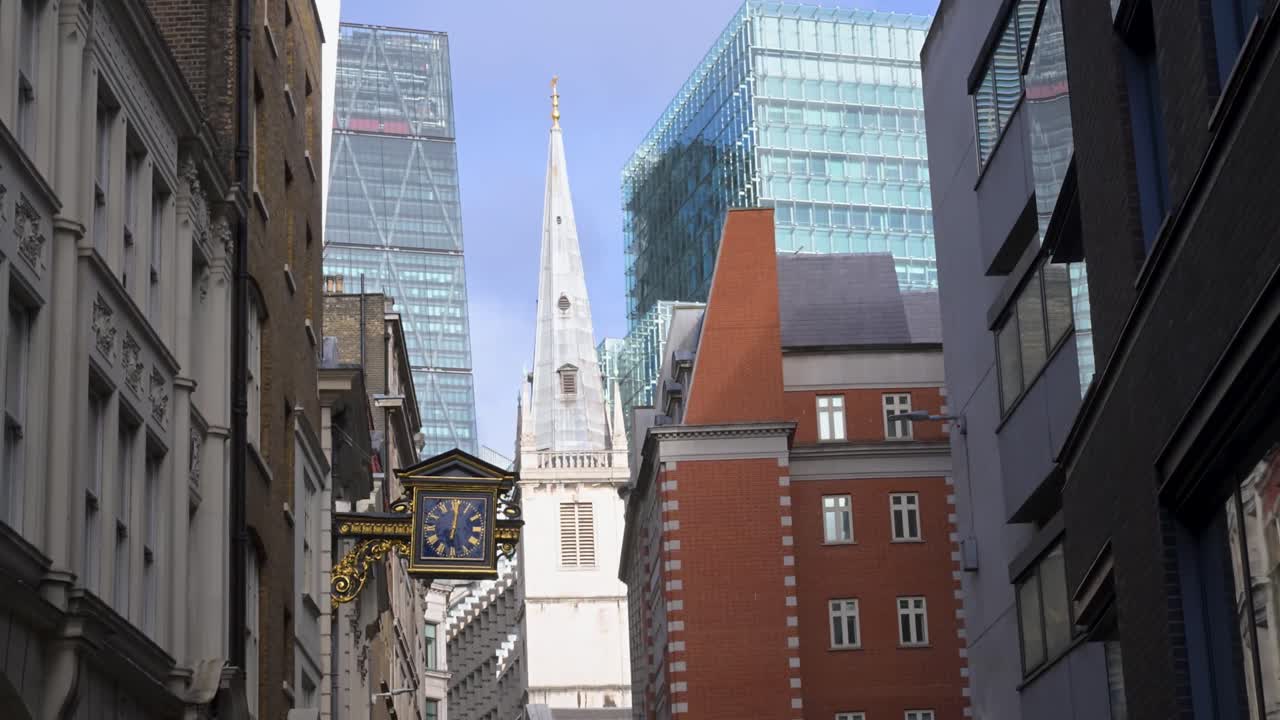 Eine Straßenansicht der Fassade der historischen anglikanischen Kirche St Mary at Hill und ihres ikonischen, hervorstehenden Glockenturms in den engen Gassen der City of London.