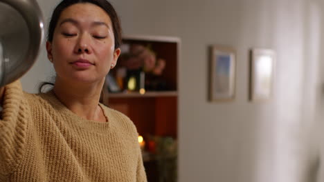 close up of woman at home in kitchen preparing healthy vegetarian or vegan meal putting sliced tofu on board into pan