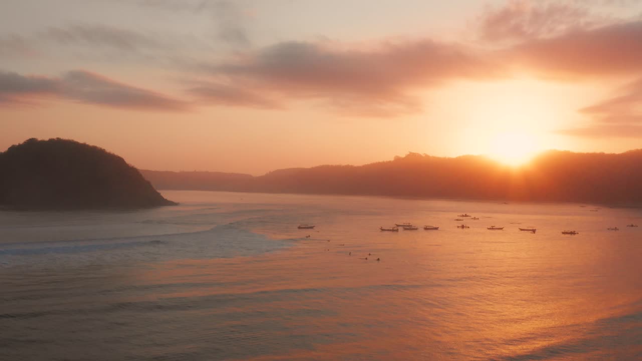 롬복에 있는 게루푹의 서핑 장소에서 일출, 어선과 서퍼가 있는 만의 전망