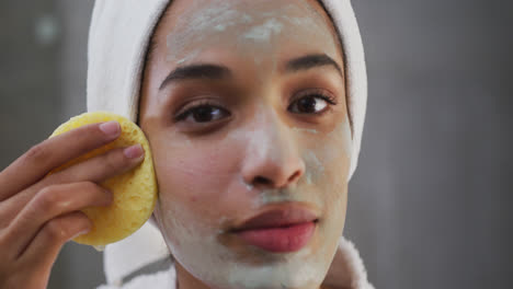 close up of mixed race woman applying face mask in bathroom