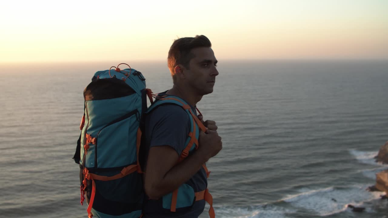 mochiler masculino activo caminando a lo largo de un acantilado