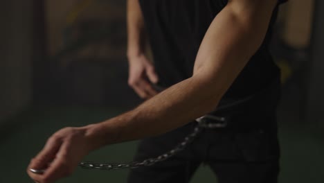 man lifting kettlebell using belt and metal chain