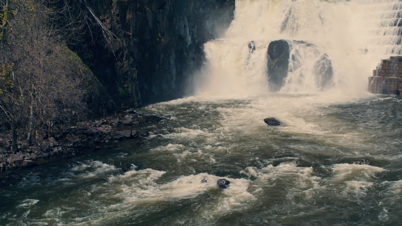 medium shot of bottom of new croton dam with powerful waterfall and stepped spillway leading down to the river. static. Slow motion 40