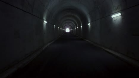 Langsamer-Flug-In-Einem-Langen-Tunnel-In-Den-Bergen-Mit-Licht-Am-Horizont