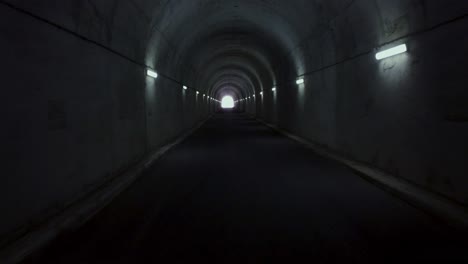 slow flight inside long tunnel in the mountains with light in the horizon