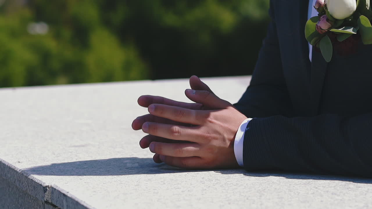 lo sposo nervoso in abito con un piccolo bouquet aspetta il matrimonio