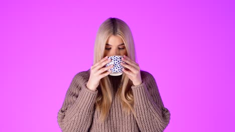 Portrait-Of-Pretty-Blonde-Woman-Enjoying-Drinking-From-Coffee-Mug,-Looking-At-Camera-Against-Pink-Background,-Studio-Shot