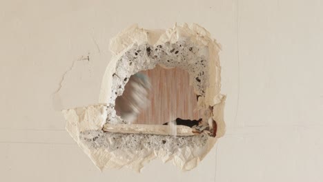 male contractor making a hole with hammer inside concrete wall, static close up shop