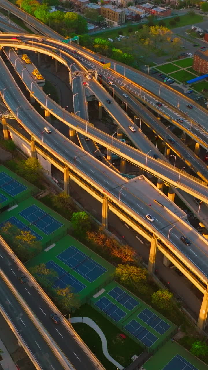 Twirling motorways with cars running over. Busy roads amidst the city. View from top. Vertical video