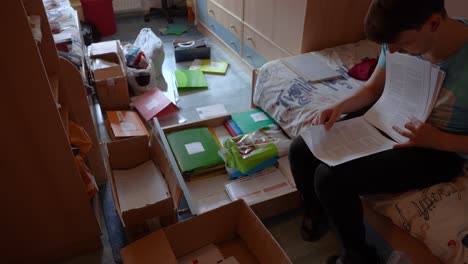 timelapse shot of a man sorting and cleaning a small bedroom, with documents and boxes laying around the room