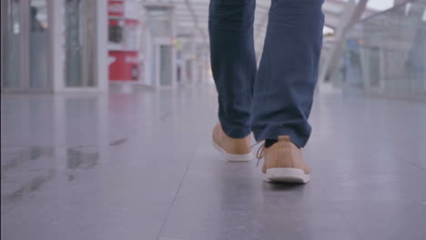 vista recortada del hombre en zapatillas de deporte caminando en el pasillo ligero