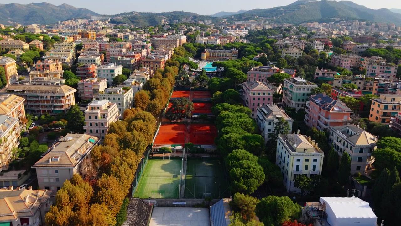 Vista aérea sobrevoando um parque urbano e quadras de tênis em Gênova em um dia ensolarado de verão.