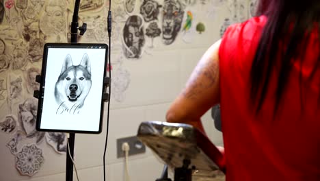 client's arm prepped for detailed husky portrait tattoo using digital reference. rack focus