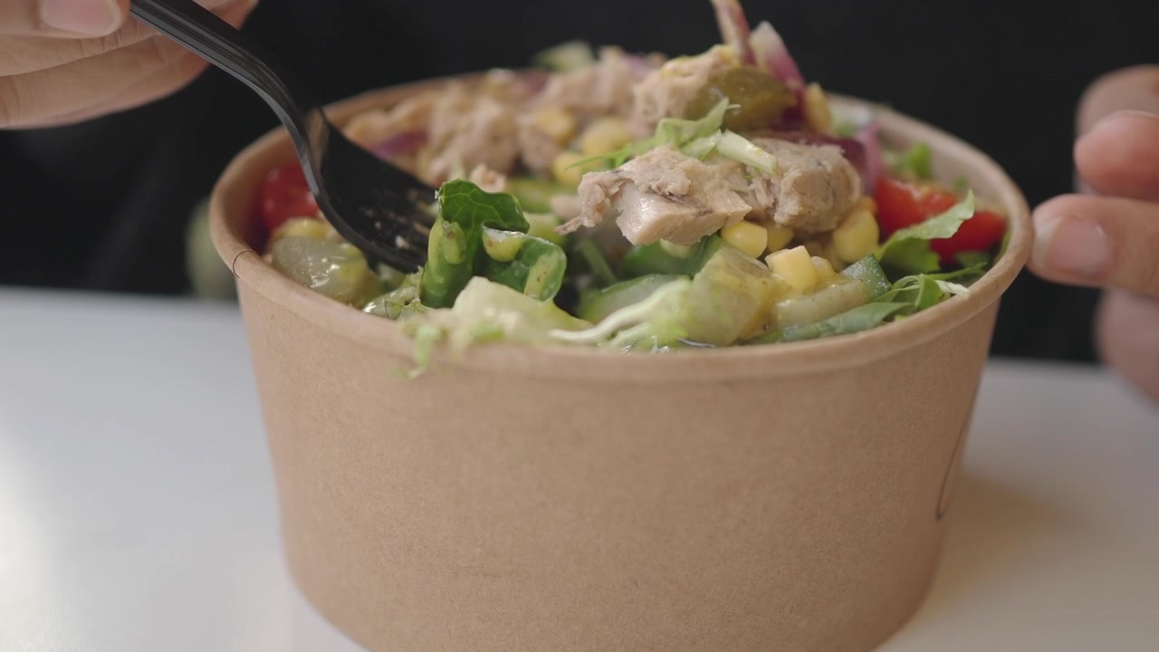 Person Eating Fresh Tuna Salad from a Paper Bowl