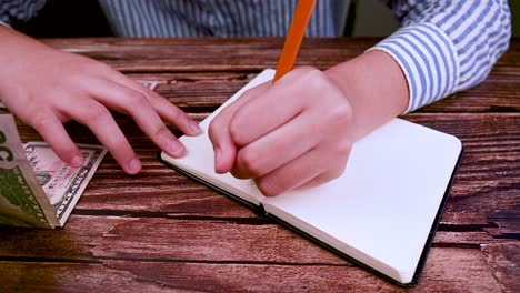 mixed race teenager saving american money and doing notes.