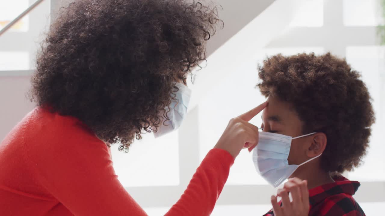 madre con máscara facial abrazando a su hijo en casa