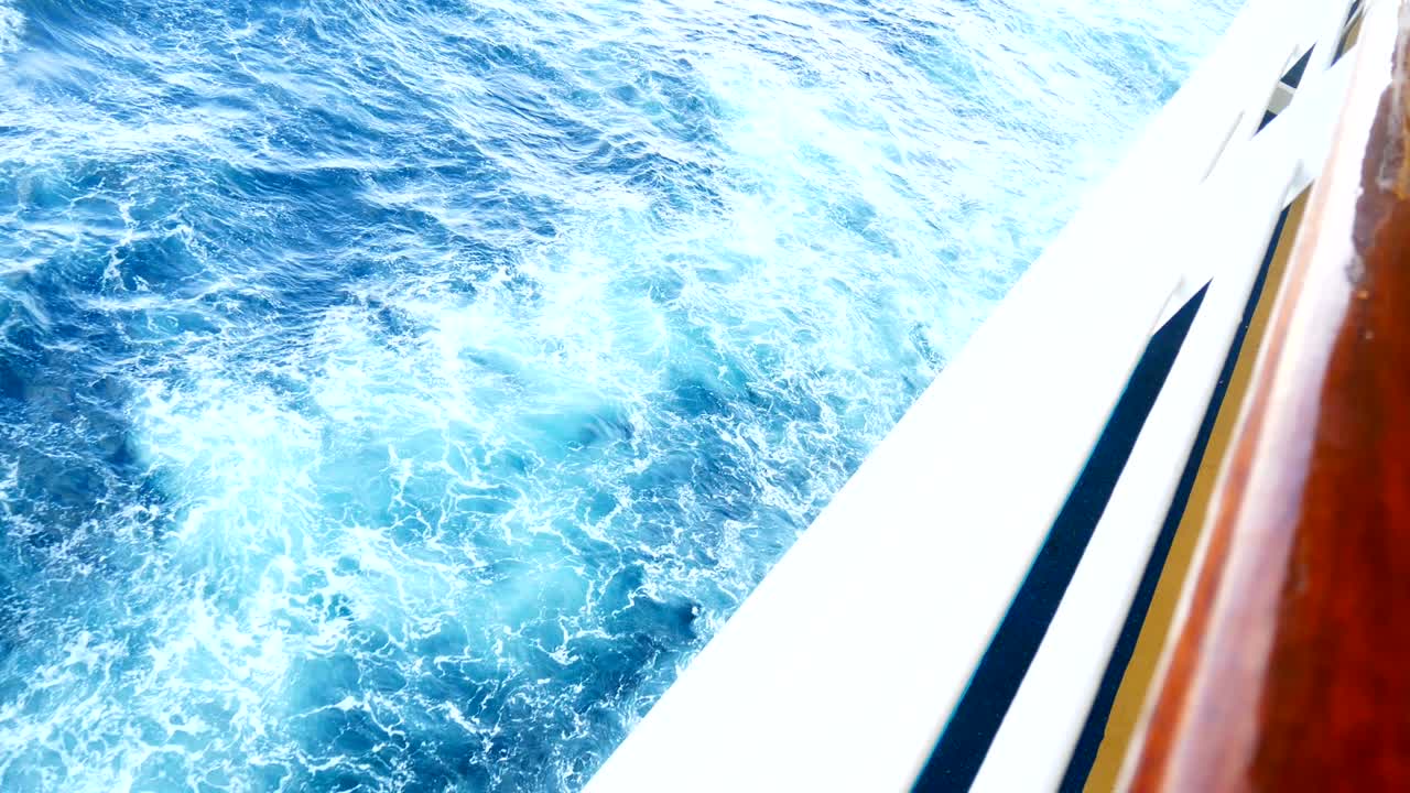 4k loop de imágenes. navegando en el viento a través de las olas. barco de vela disparado en el mar azul áspero a toda velocidad mientras el mar está pasando.