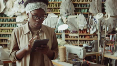mujer afroamericana trabajando en una tableta en un taller de zapatero