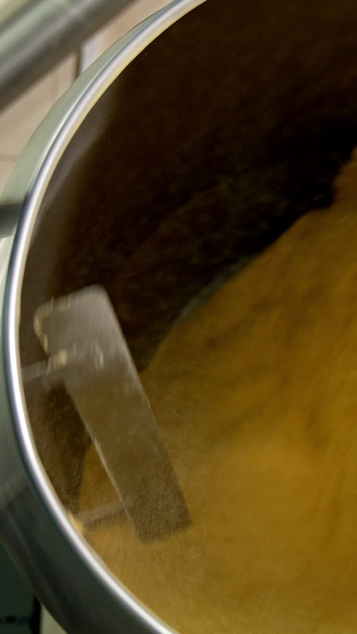 Yellow substance being mixed in a big metal tank. Sweet corn desserts production at the food factory. Vertical video