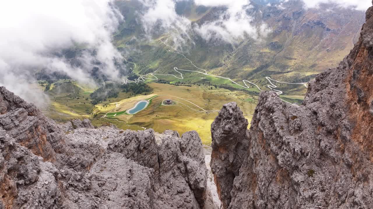 Flight from the Sella Mountains down to the Val di Fassa valley. Down below, there are switchbacks leading to the mountain passes