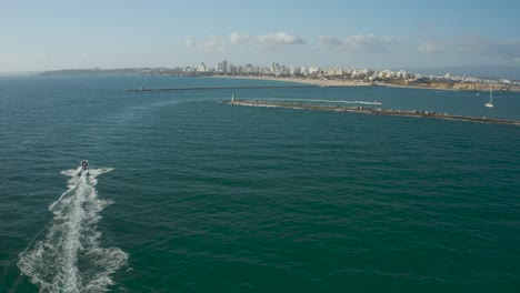 speedboat cruising on atlantic coastline towards portimao, aerial following