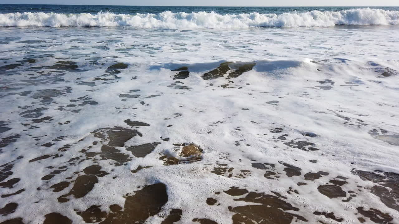 Rocks on the beach in foamy water