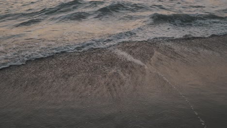 Water-receding-toward-the-sea-as-subsequent-Pacific-waves-burst-at-the-sandy-La-Punta-beach-in-Mexico-during-sunset