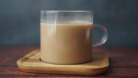 close up of a glass mug of coffee or tea on a wooden coaster