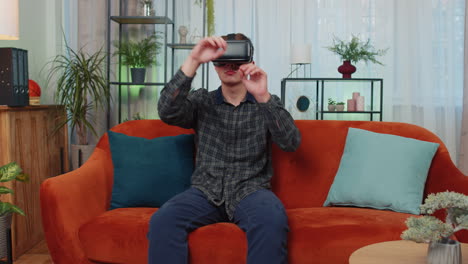 man wearing a vr headset sits on a couch, looking up in amazement.