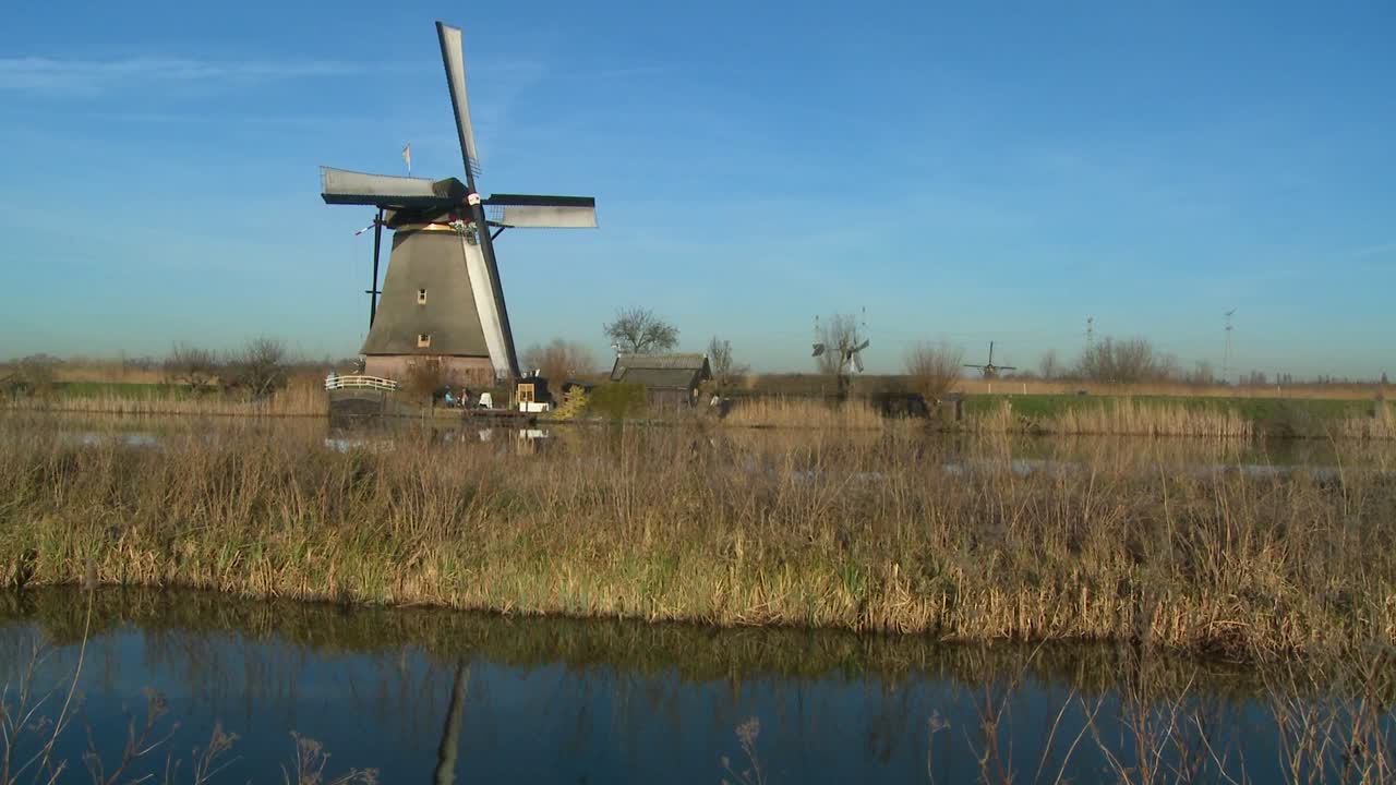 네덜란드의 운하와 잔디 위로 풍차가 떠오른다