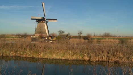 a windmill rises above a canal and grass in holland