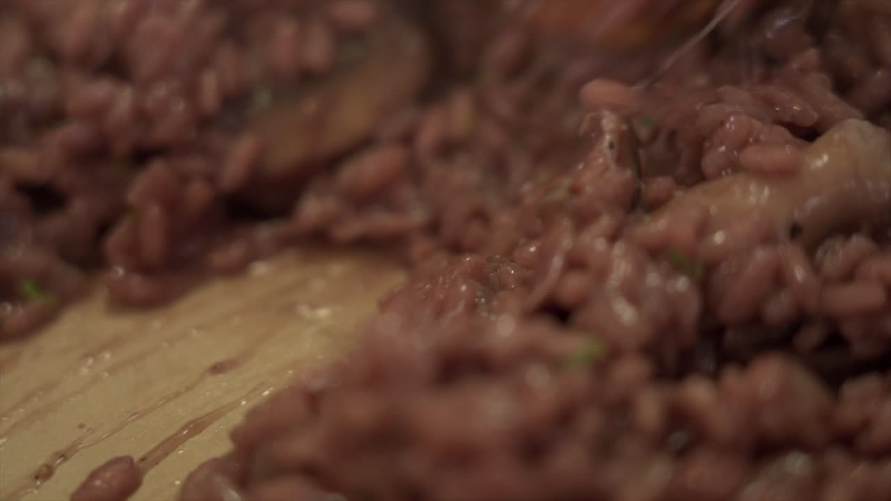 mezclando risotto cremoso de vino tinto con una nuez de mantequilla derritiéndose en el centro