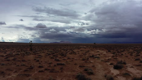 a rare day in the mojave desert with rain clouds gathering over the mountains and basin - aerial push forward