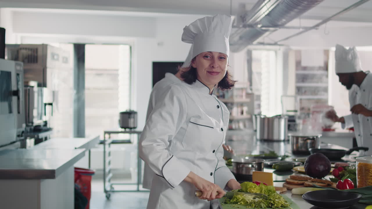 Portrait of female cook cutting green celery in gourmet kitchen