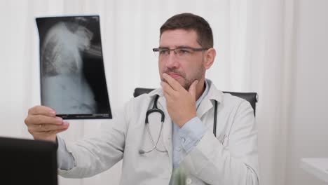 médico sentado dentro de su oficina y leyendo la placa de rayos x del paciente