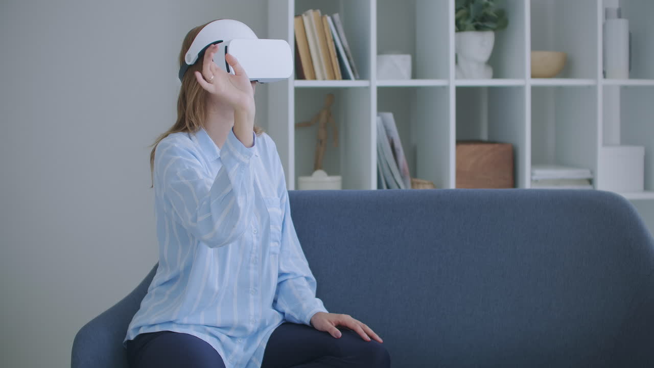 mujer joven alegre con auriculares de realidad virtual viendo una película de video 360 vr sentada en la cama en casa. retrato de mujer joven con gafas de realidad virtual sentada en el sofá en casa.