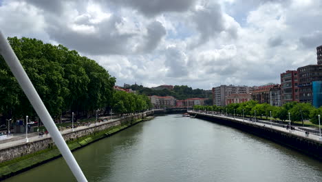 Aerial-walk-over-Bridge-in-Bilbao-City-with-Nervion-River-view-and-residential-area-during-cloudy-day