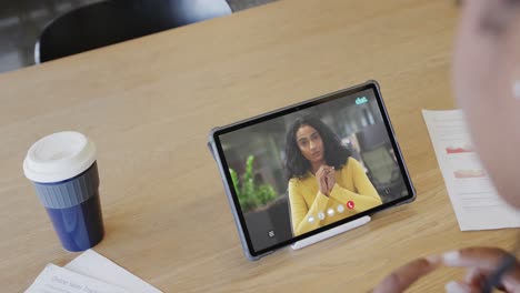 Caucasian-businesswoman-on-tablet-video-call-with-african-american-female-colleague-on-screen