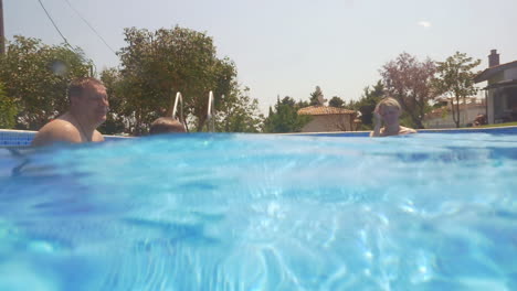 boy learning swimming in the pool with his parents and granny