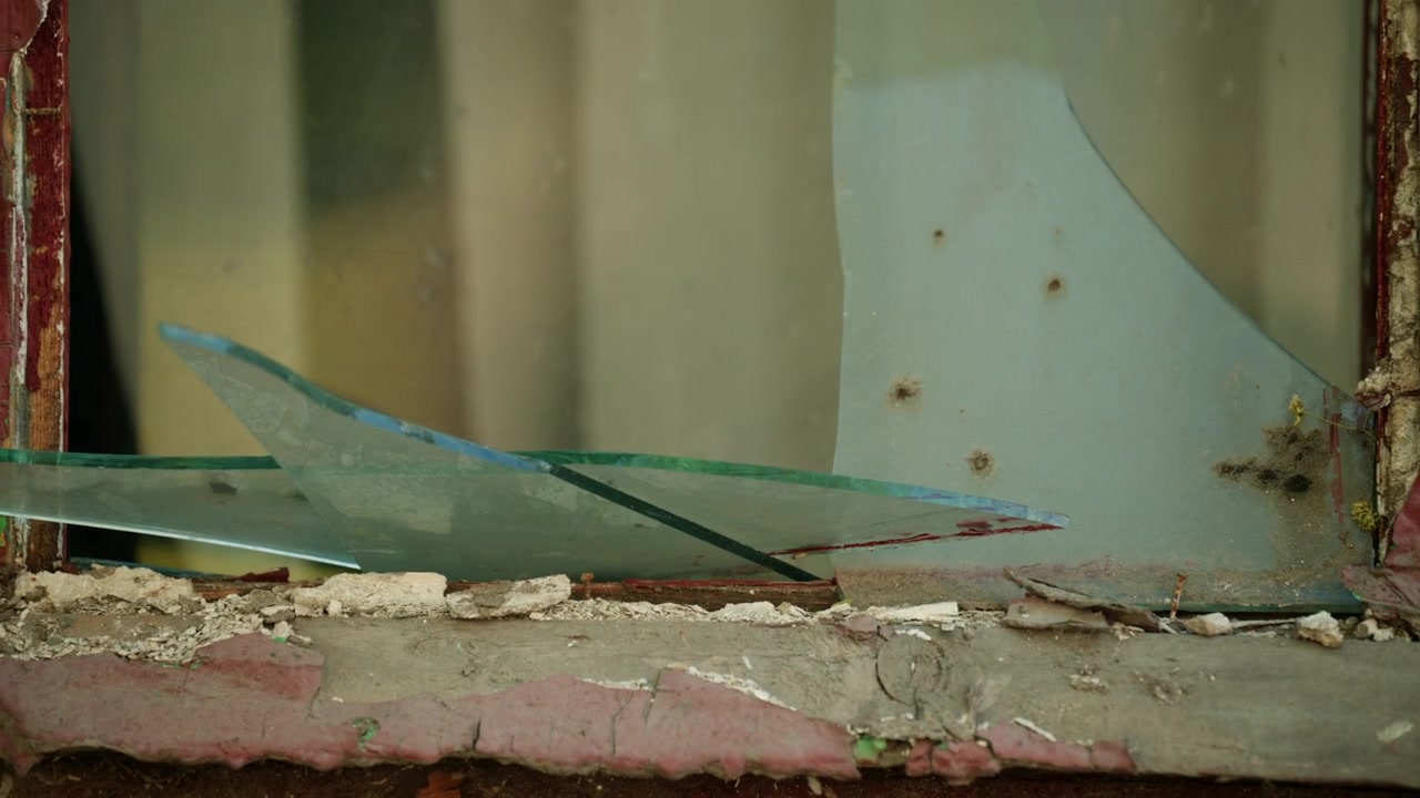 Close up view of a damaged window with shattered glass in an old building