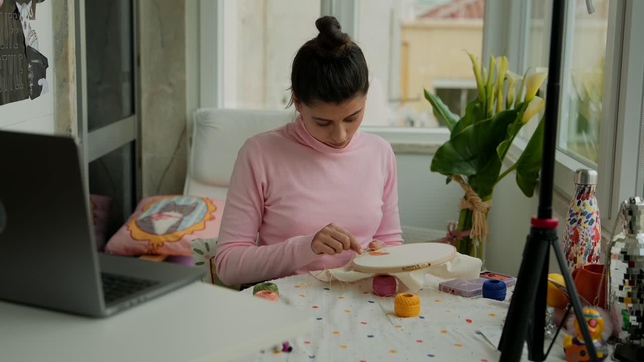 Giovane donna concentrata sul ricamo a casa