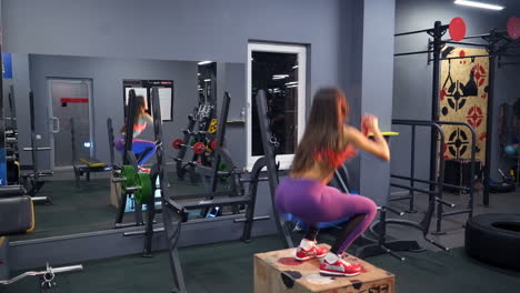 fit young woman box jumping at a crossfit style. female athlete is performing box jumps at gym
