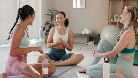 three women in yoga clothes sitting on yoga mats