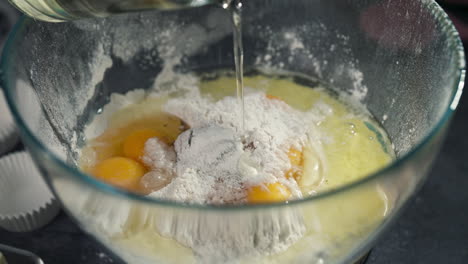 close up of cupcake batter mixed with oil inside of glass bowl, slow motion