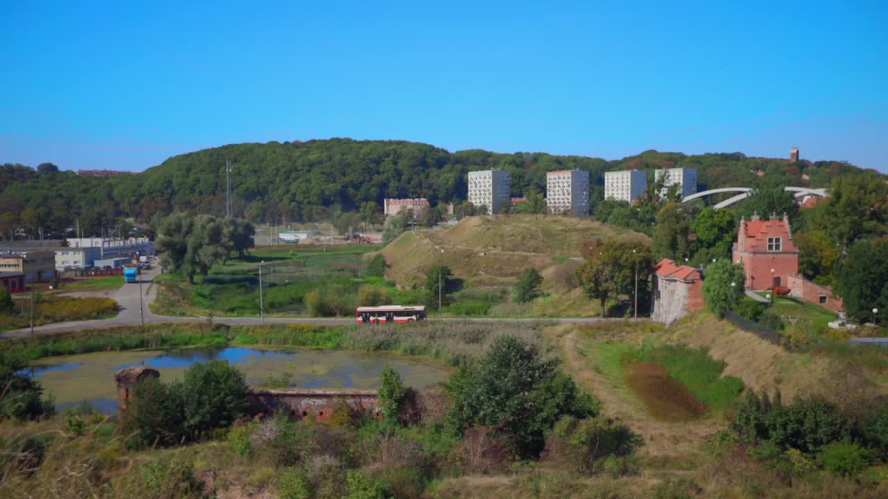 Static shot showing driving bus,old buildings, natural lake and residential blocks in background.Gdansk,Poland.